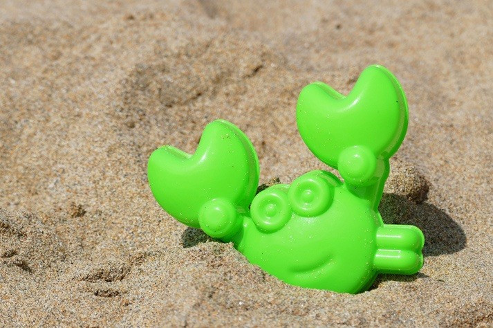 Green toy crab in the sand on Ibiza beach